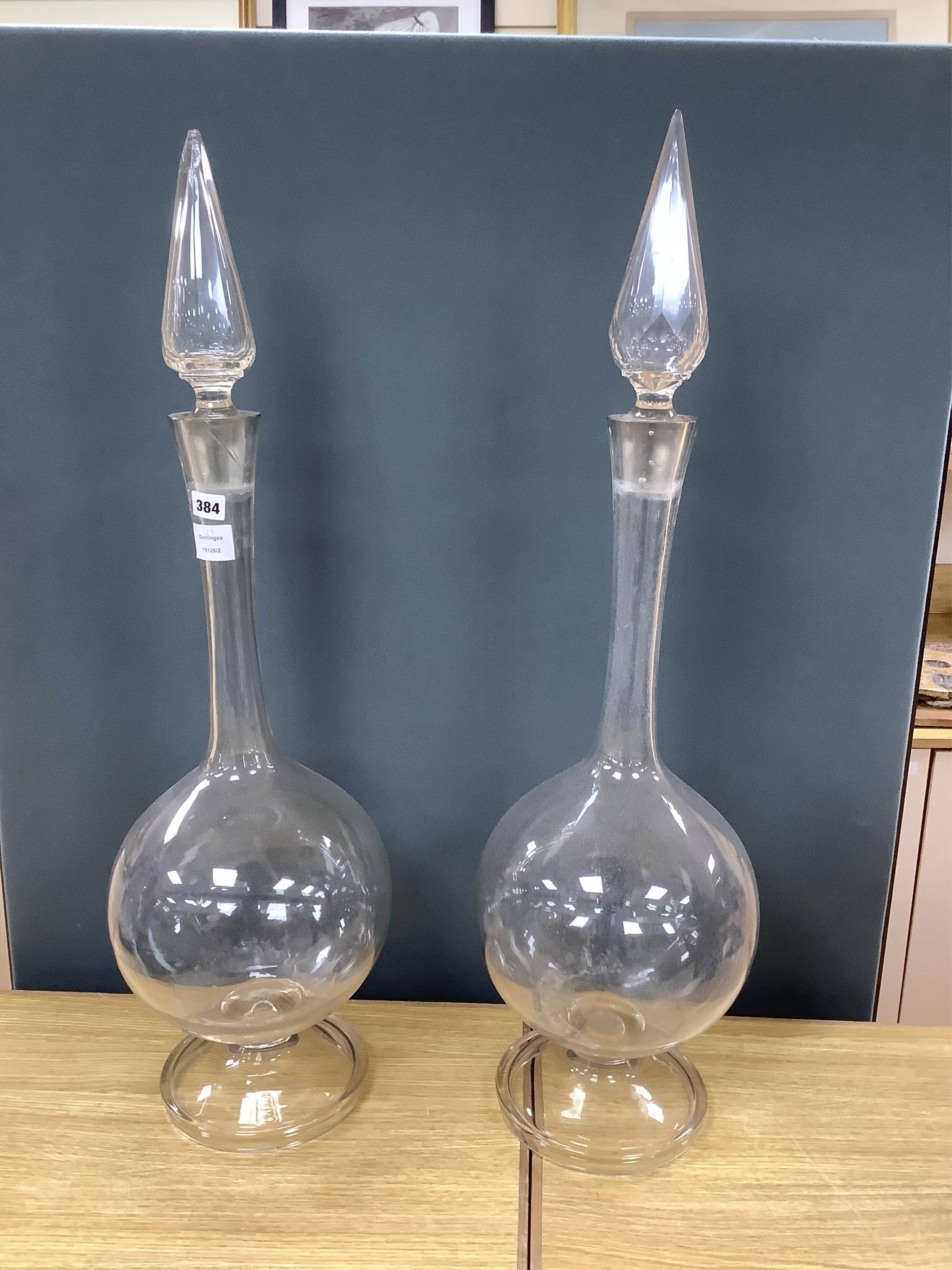 A pair of large clear glass chemist window display bottles and stoppers, one with chip, 90cm high